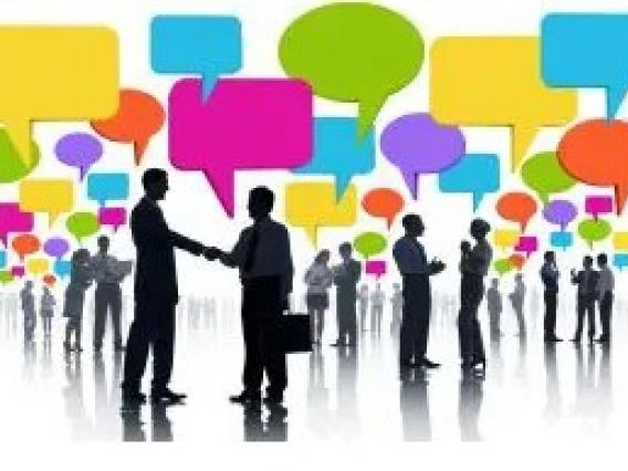 Silhouettes of people networking and shaking hands with colorful speech bubbles above them, representing communication and collaboration.